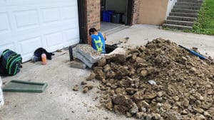 Digging through concrete in front of a garage