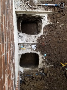 Top down of two foundation repair holes on the side of a house