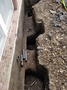 Installing foundation piers in trench on side of house