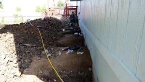 Installing foundation piers in holes dug onto side of home