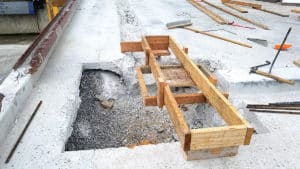Hole in wet concrete with wooden support over it
