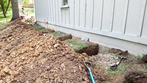 Holes dug near side of house to begin leveling foundation