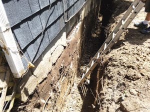 Ladder descends into trench near house edge