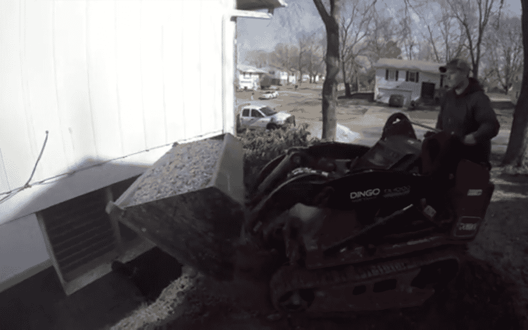 Tractor carrying gravel to put against foundation wall