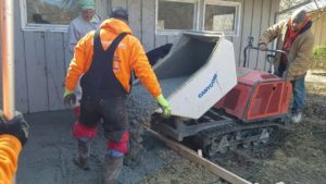 Men using a tractor to pour concrete into a mold