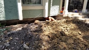 Man underneath house digging trench