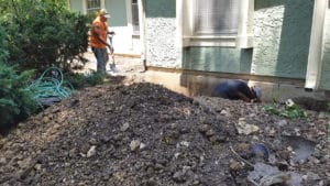 Men digging trench near house wall