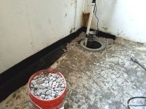 Sump pump in basement corner surrounded by rocks