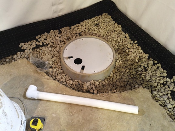 Sump pump base in floor surrounded by rocks
