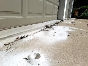 Sunken and cracked concrete slab near garage door before polyjacking repair